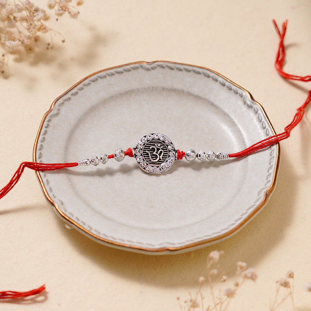 Madhoor Om Rakhi Red Silver-Tone 1 Piece